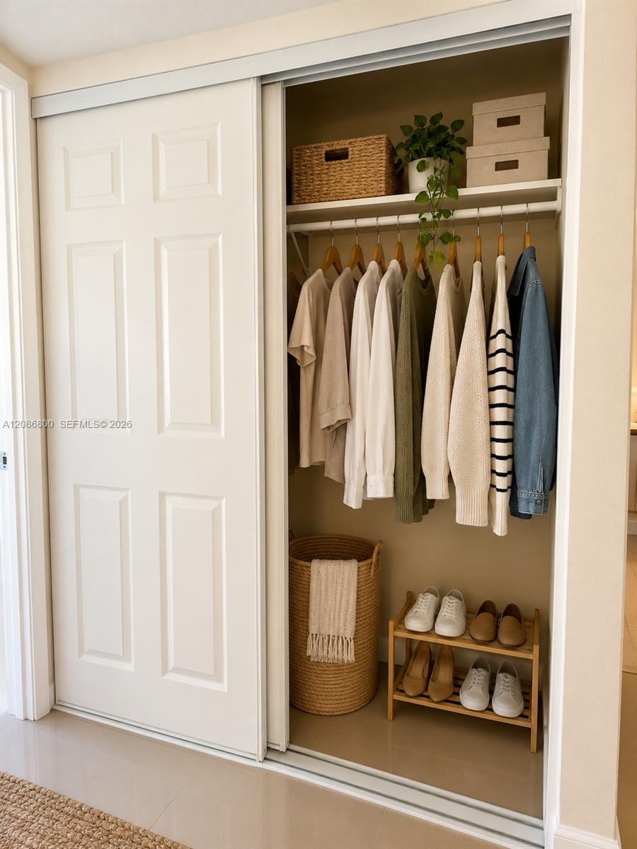 Organized closet with neutral clothing, woven storage baskets, and shoes on a small rack.