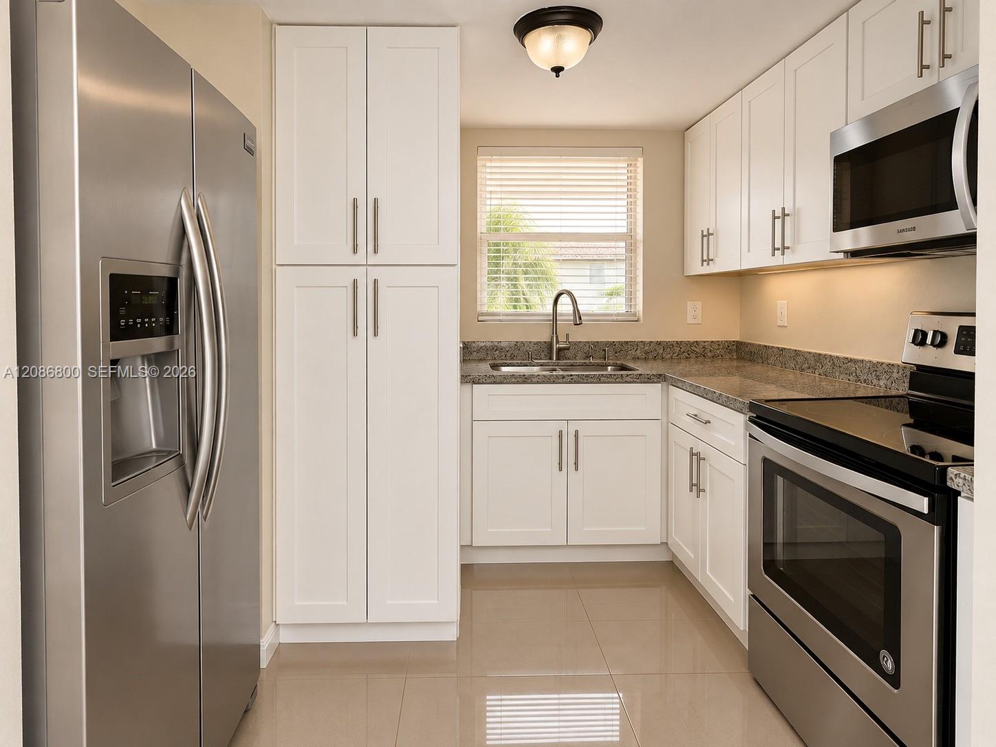 Kitchen with white cabinets, granite counters, and stainless steel appliances.