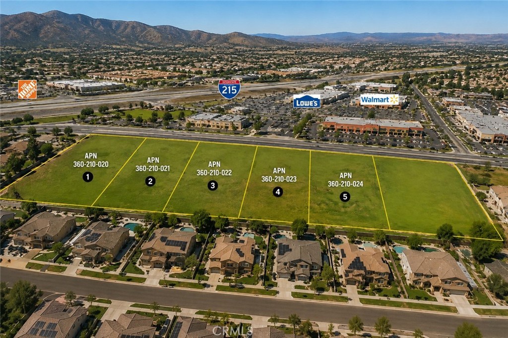 Five marked land parcels beside retail stores and Interstate 215, with mountains in the distance.
