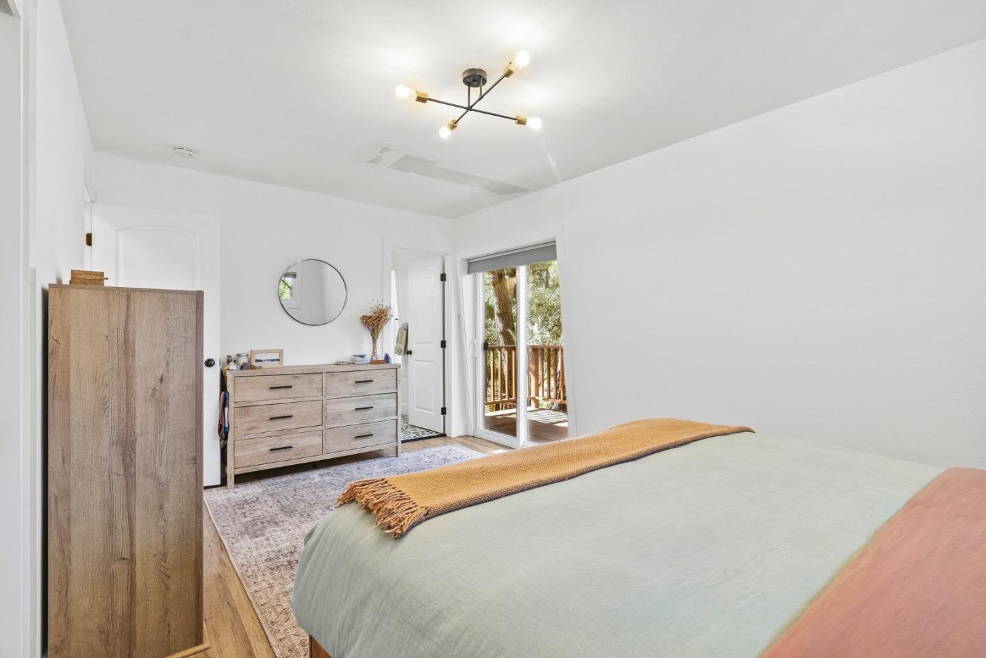 Staged bedroom with light wood furnishings and a sliding glass door to a balcony.