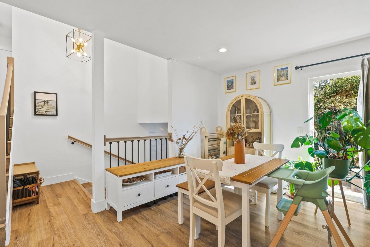 Dining area with a wooden table, white chairs, built-in bench, and arched glass-front cabinet.