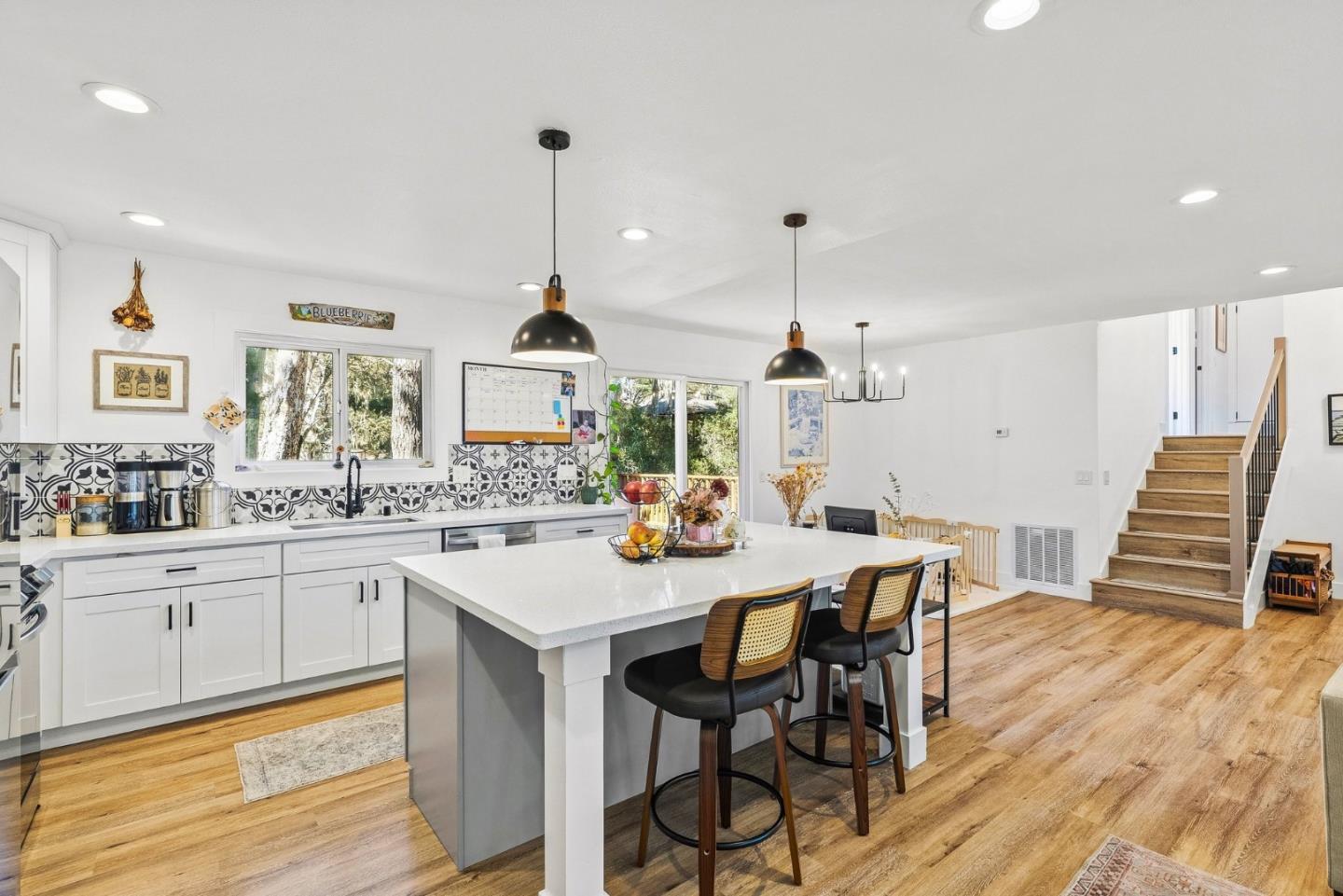 Bright kitchen with a large island, patterned tile backsplash, and warm wood floors.