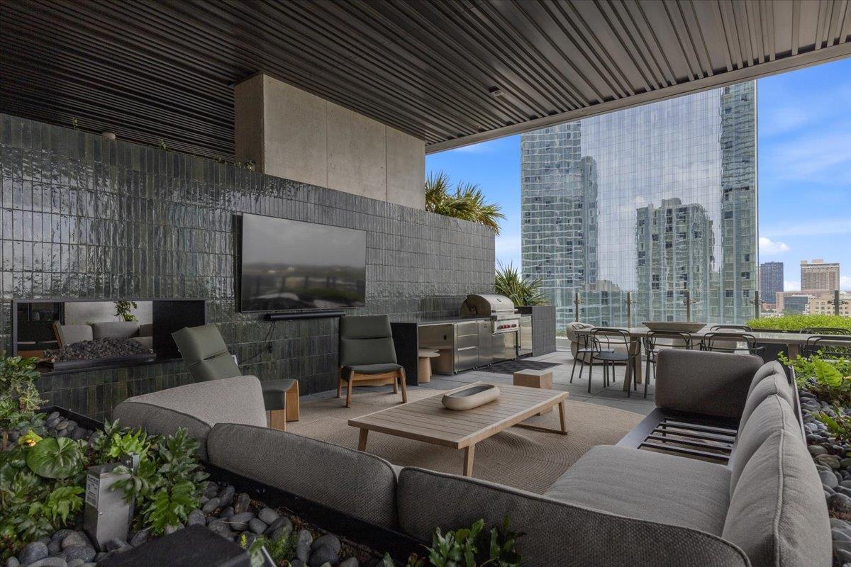 Covered terrace with lounge seating, built-in grill, and views of downtown high-rises.
