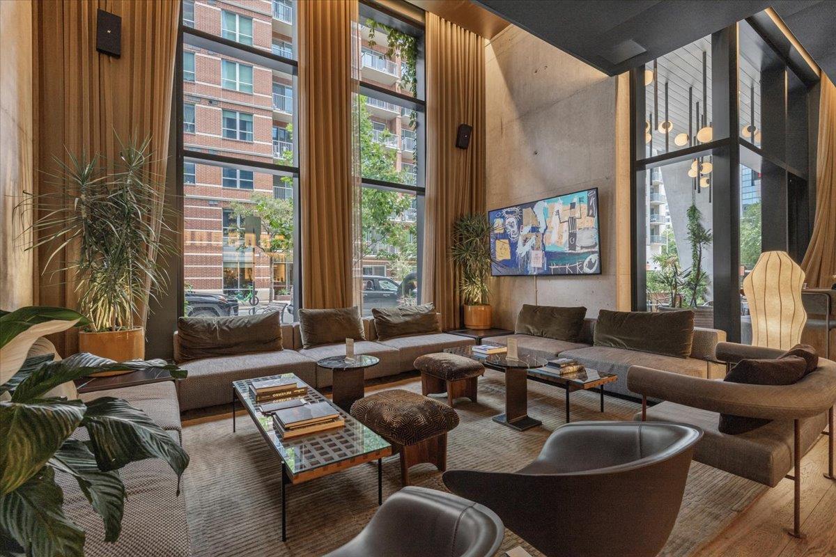 Furnished lounge with floor-to-ceiling windows, sectional seating, and colorful abstract wall art.