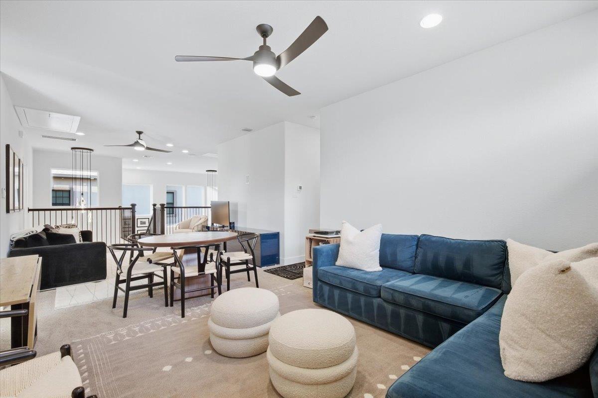 Open-plan living and dining area with blue sofas, a round table, and upholstered ottomans.