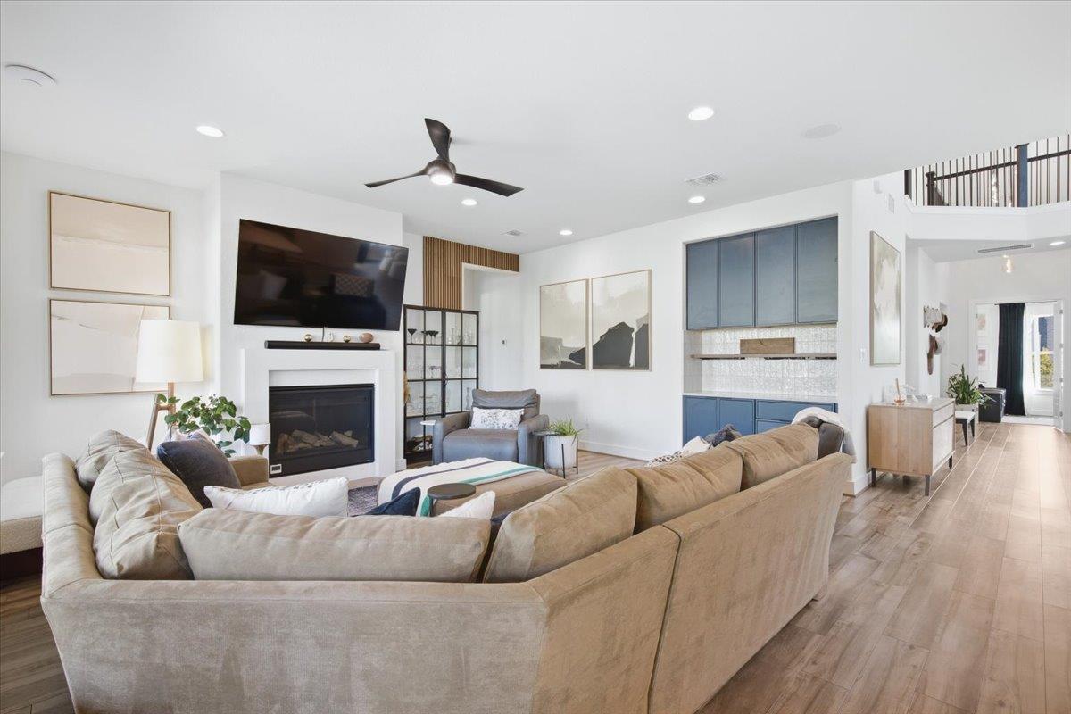 Furnished living room with a large sectional, fireplace, wall-mounted TV and blue kitchen cabinetry.