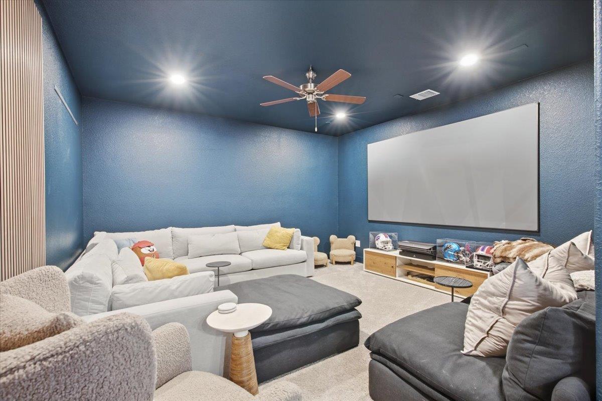 Media room with blue walls, a large projection screen, and wraparound sectional seating.