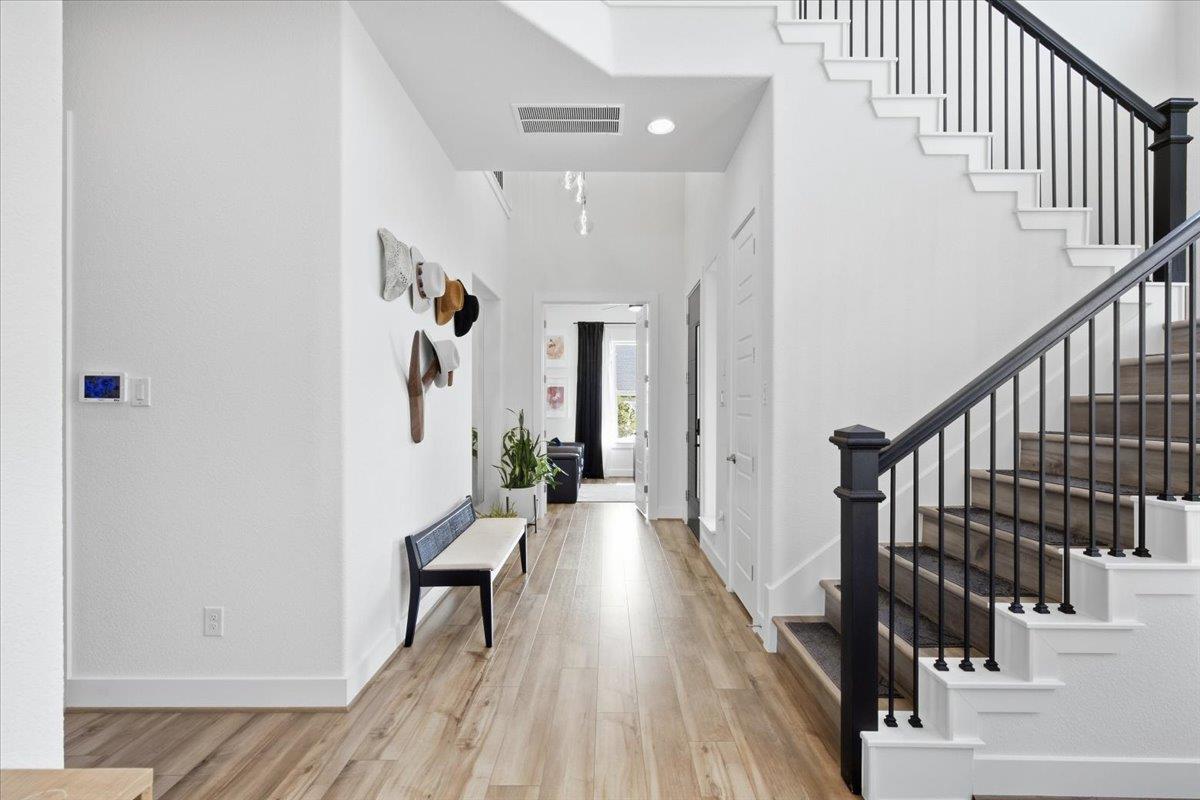 Entry hall with a bench and wall hooks beside a staircase with dark railing.