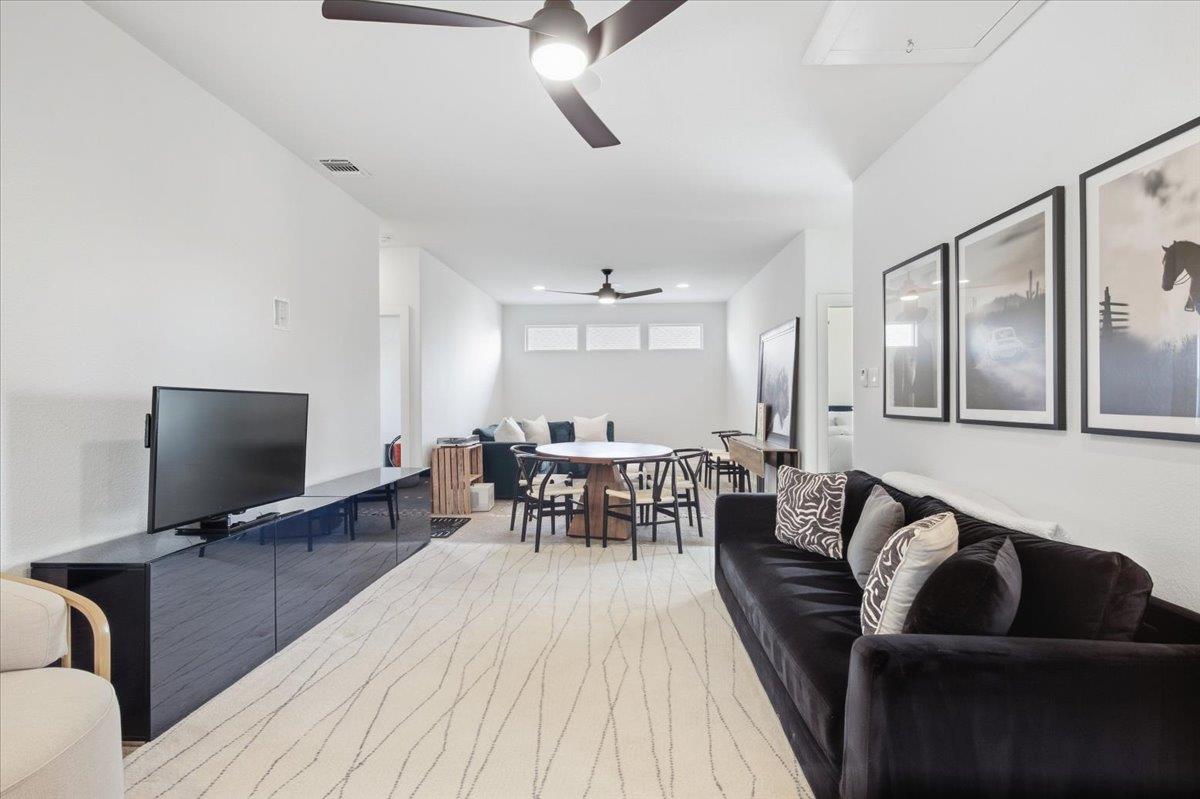 Living room with a black sofa and television, opening to a dining area with a round table.