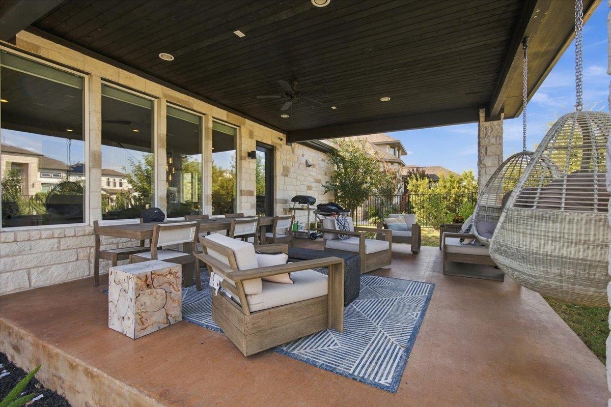 Covered patio with stone walls, outdoor lounge seating, a dining table, and a hanging egg chair.