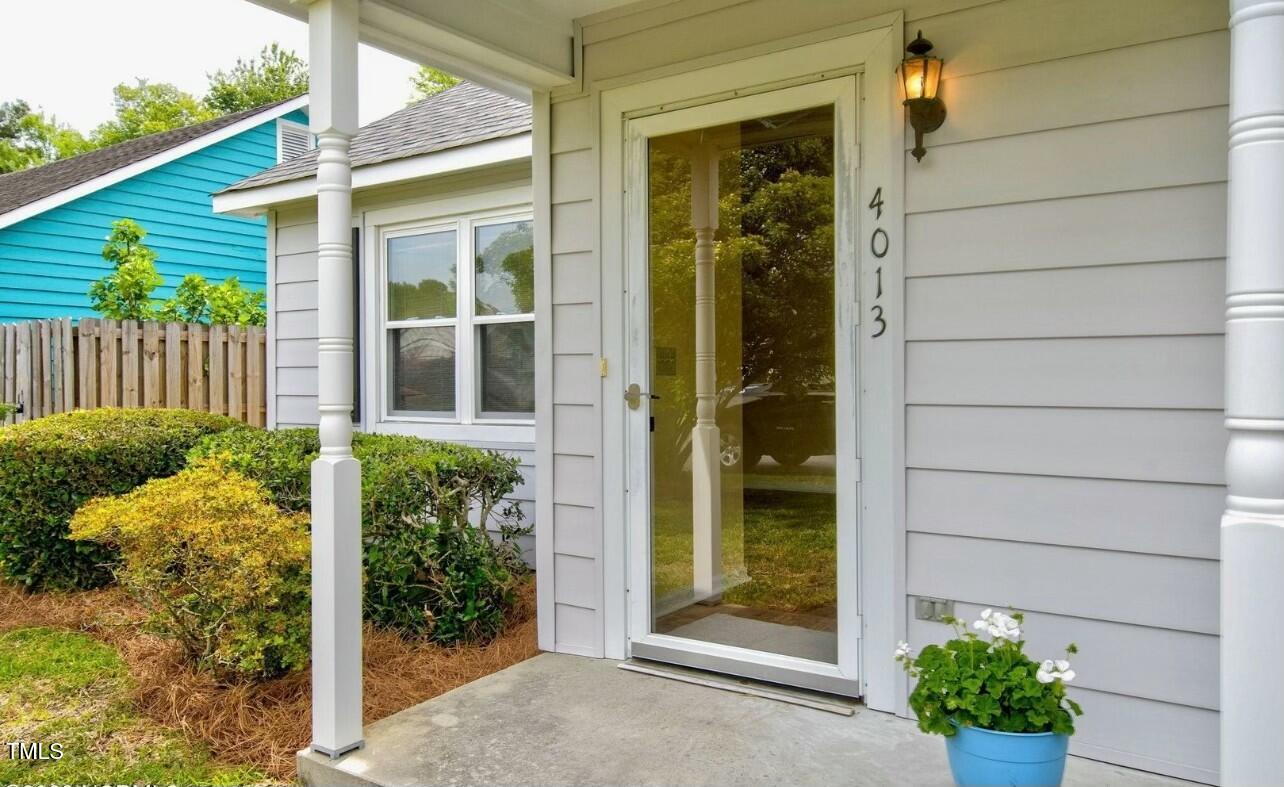 Home entrance with a glass storm door, white porch columns, and a blue planter of white flowers.