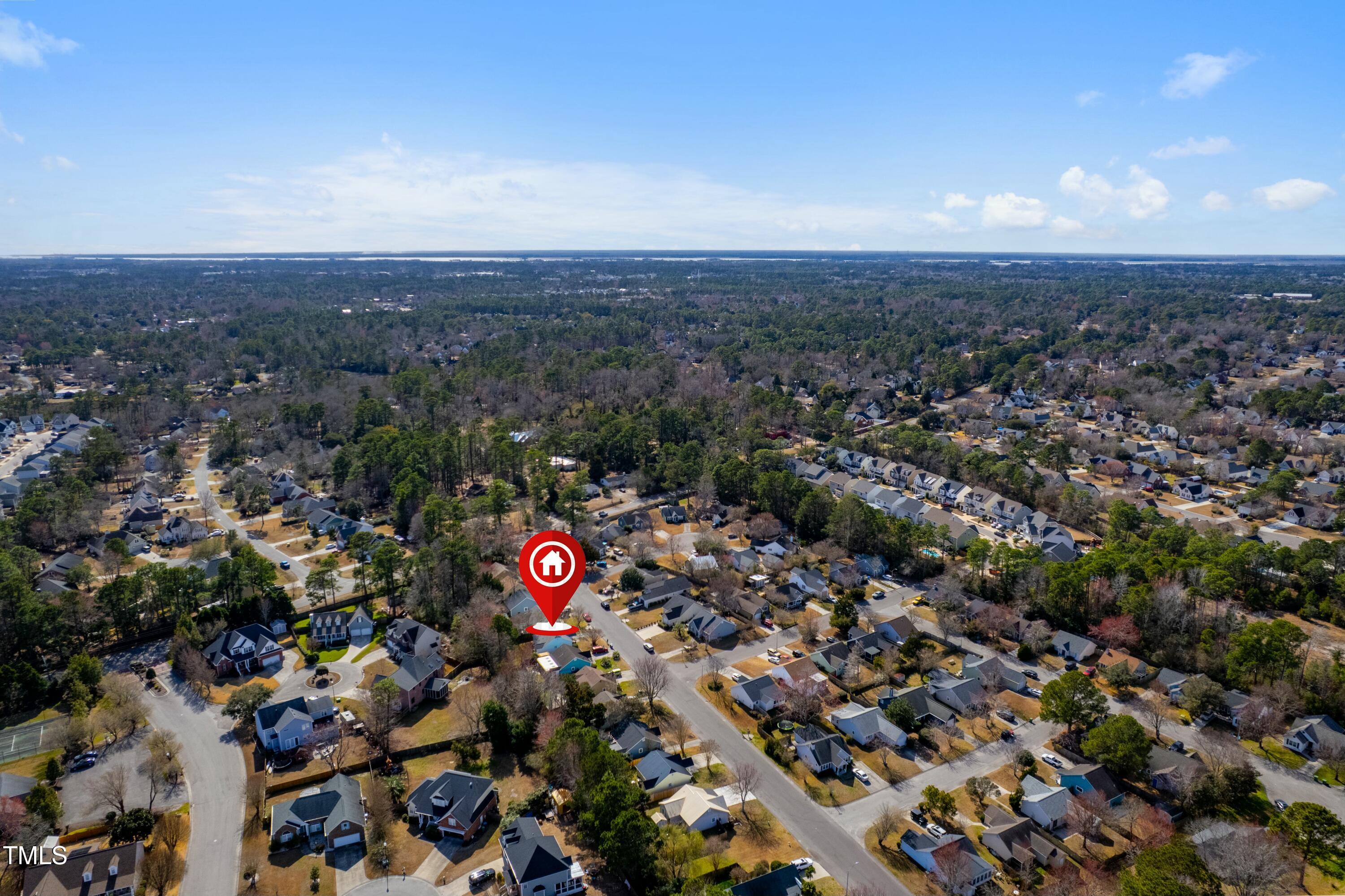 Aerial view of a wooded neighborhood with a red pin marking the property.