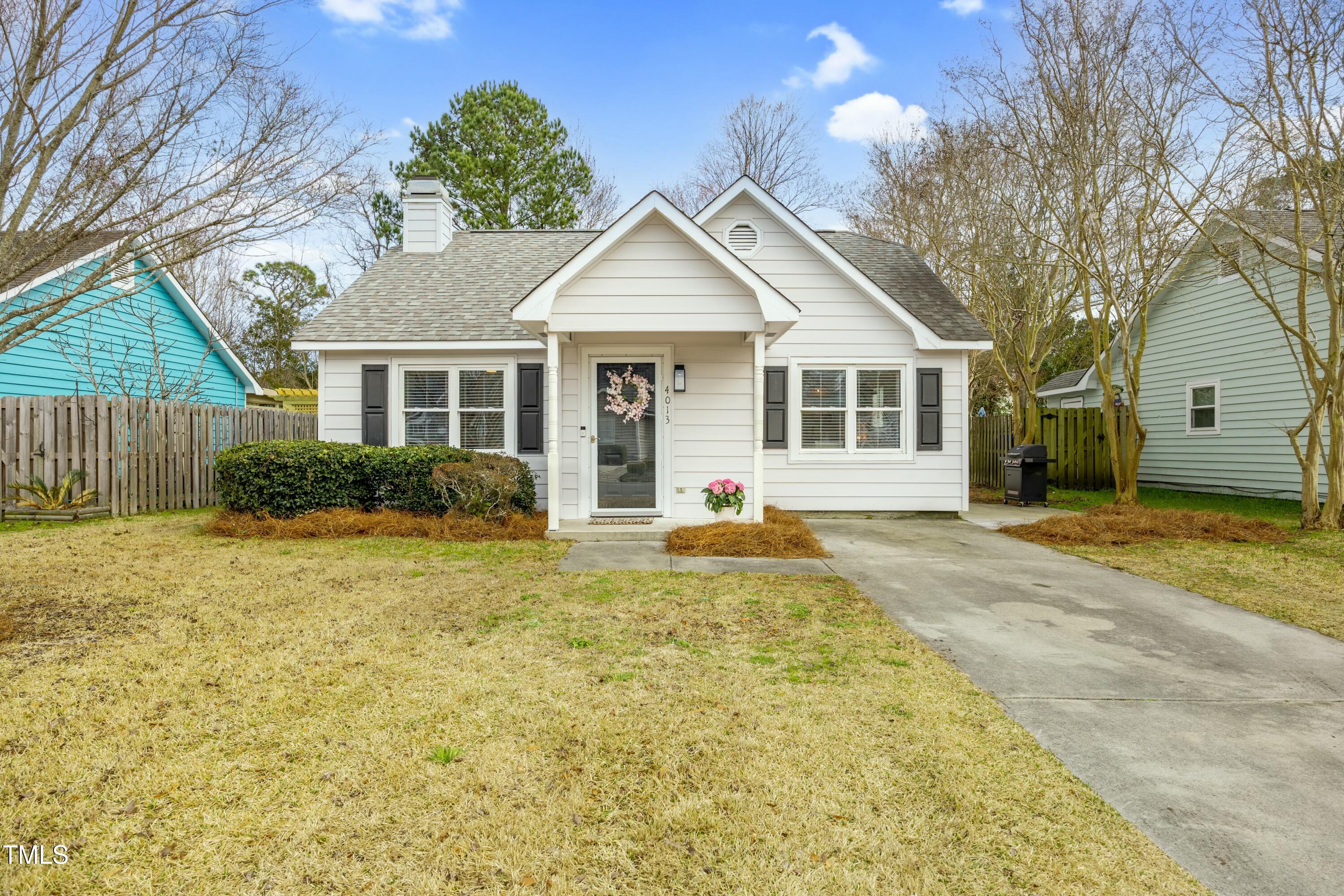 White gabled house with dark shutters, a covered entry, and a concrete driveway.