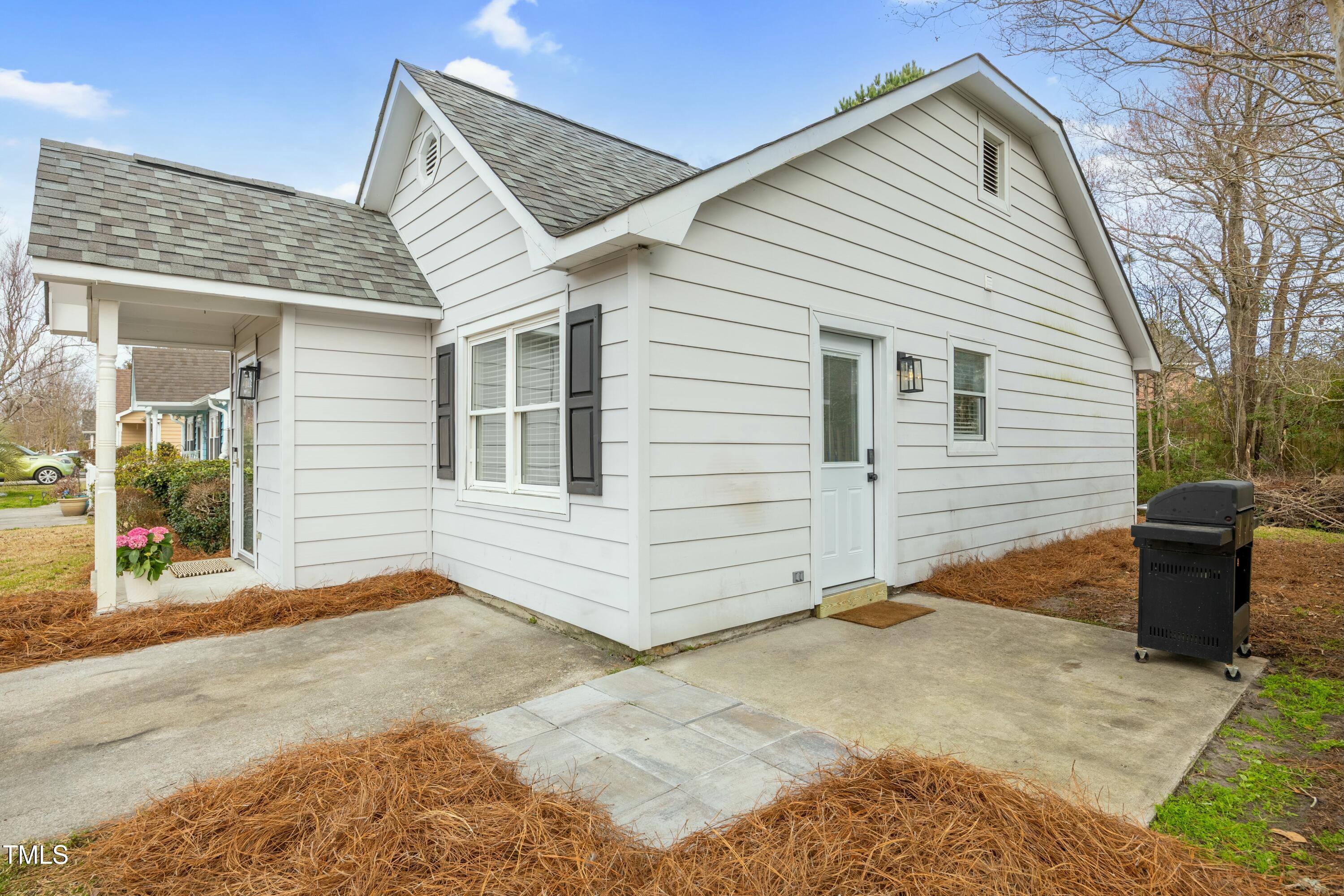 White-sided home with a covered porch, gabled roof, and concrete patio.