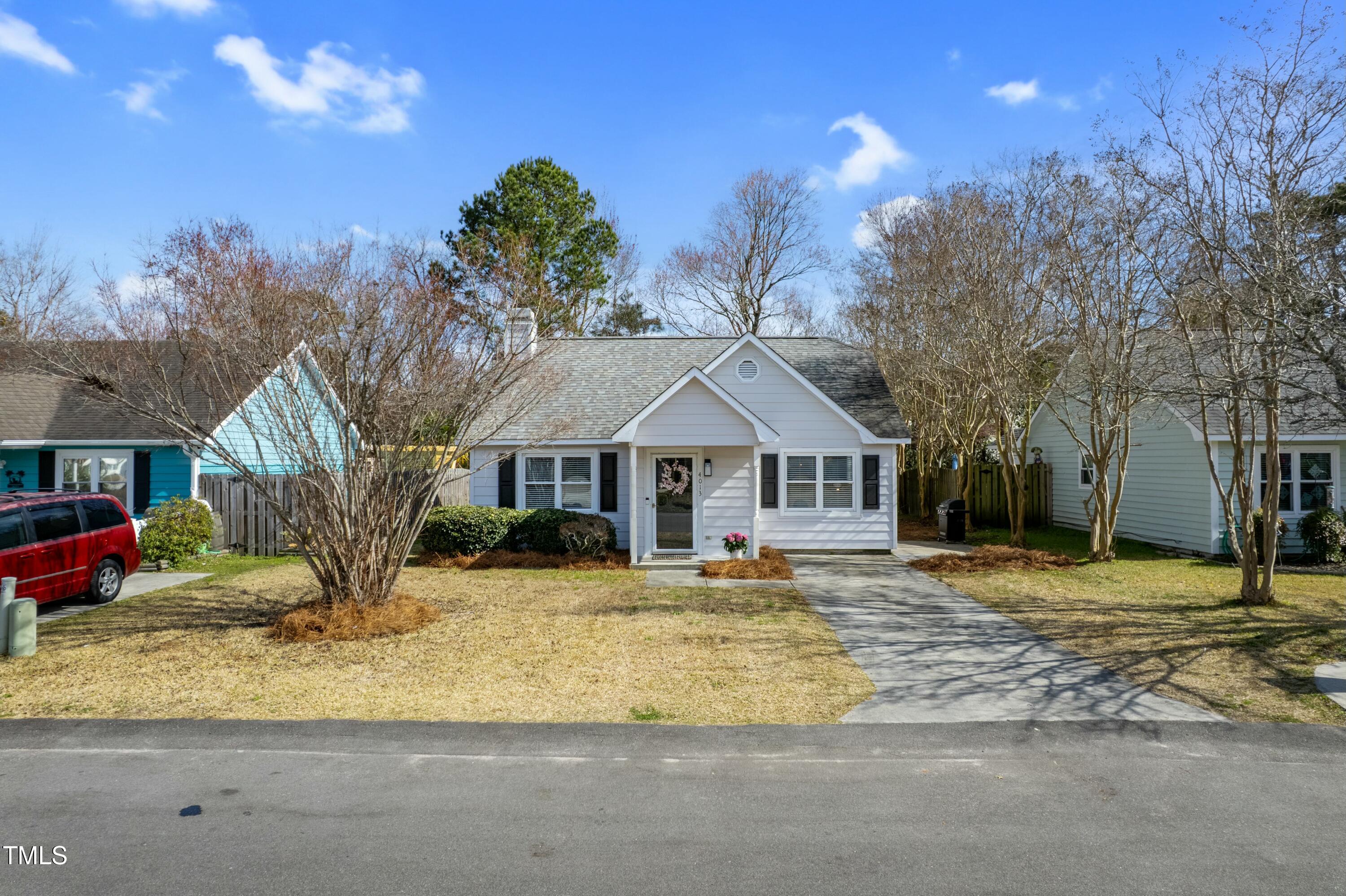 White single-story home with dark shutters, a flower-decorated entry, and a walkway to the street.