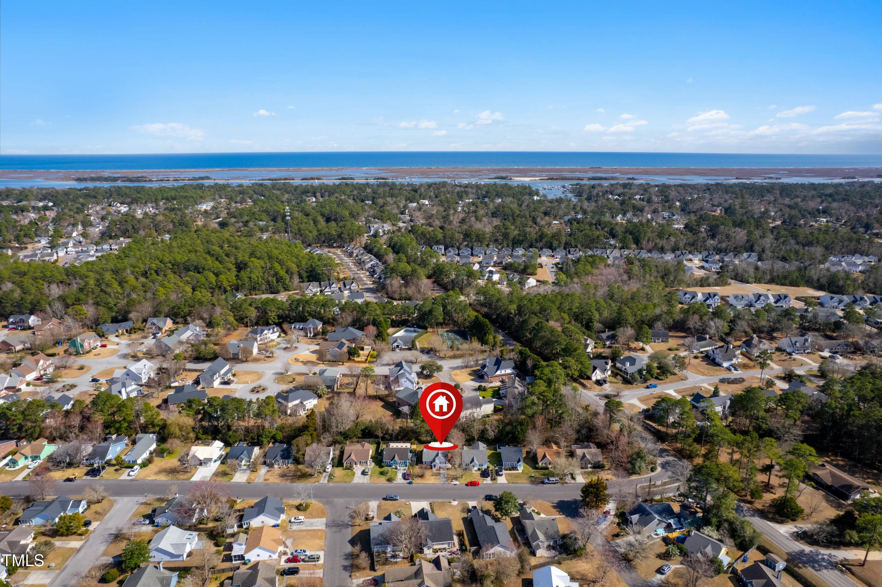 Aerial view of a marked home in a coastal neighborhood near the ocean and tidal marshes.