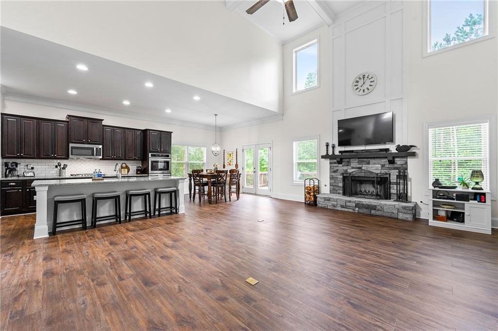 Open kitchen and living area with a large island, vaulted ceiling, and stone fireplace.
