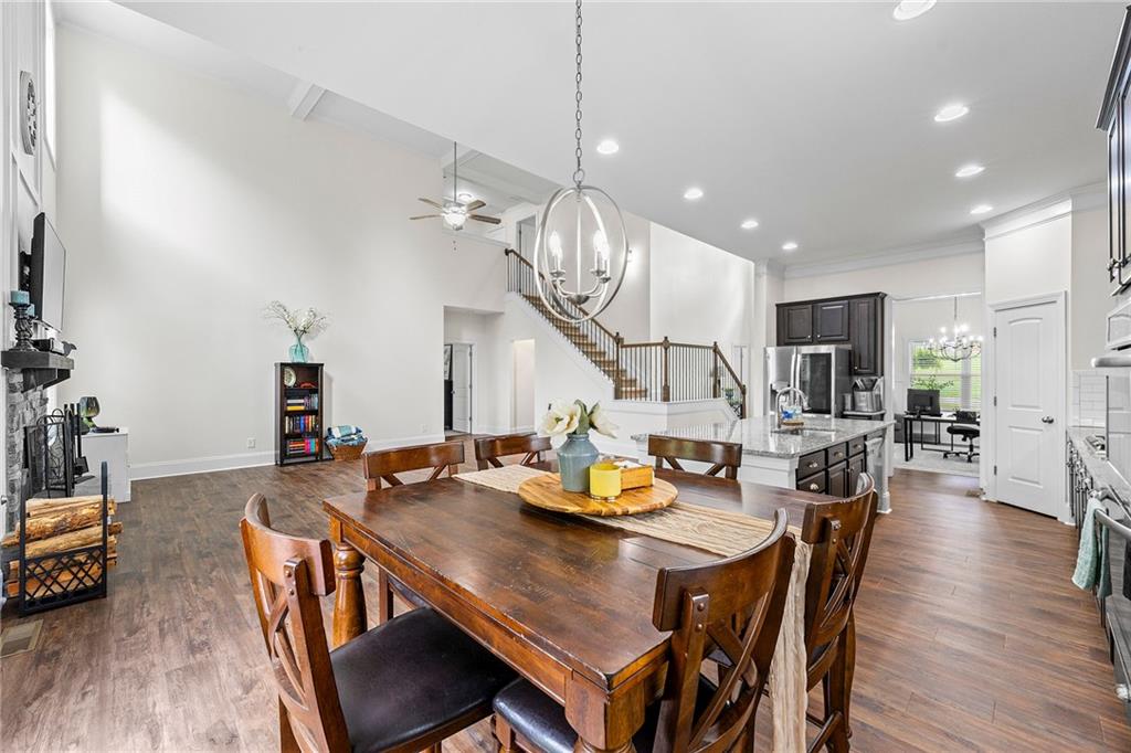 Open-plan dining room with a large wooden table, kitchen island, fireplace, and staircase.
