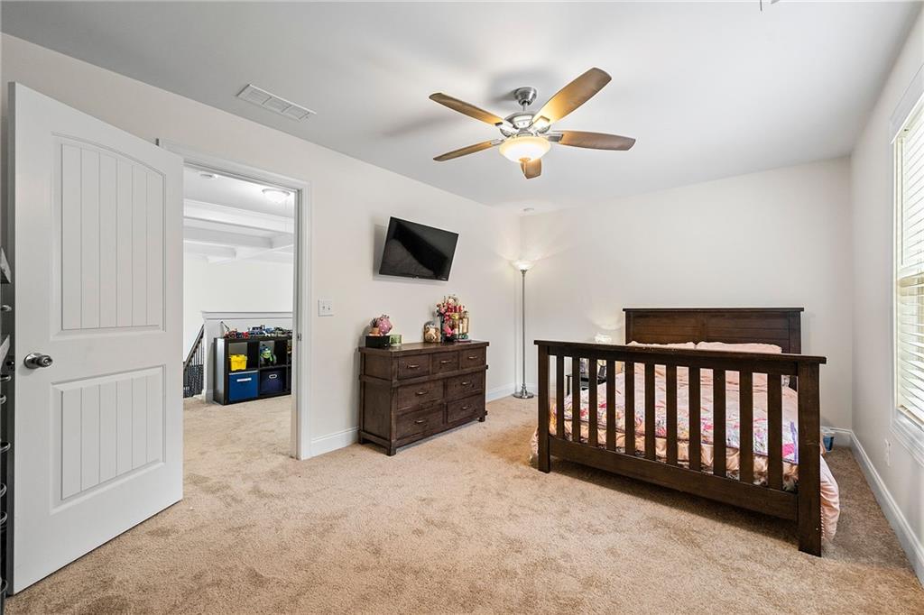 Bedroom with a dark wood bed, dresser, ceiling fan, and doorway to a play area.