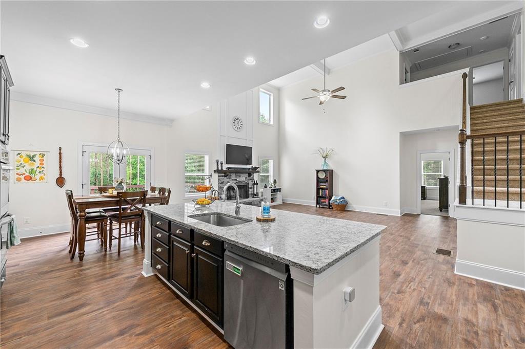 Open-concept kitchen with a granite island, dark cabinets, stainless appliances, and dining area.
