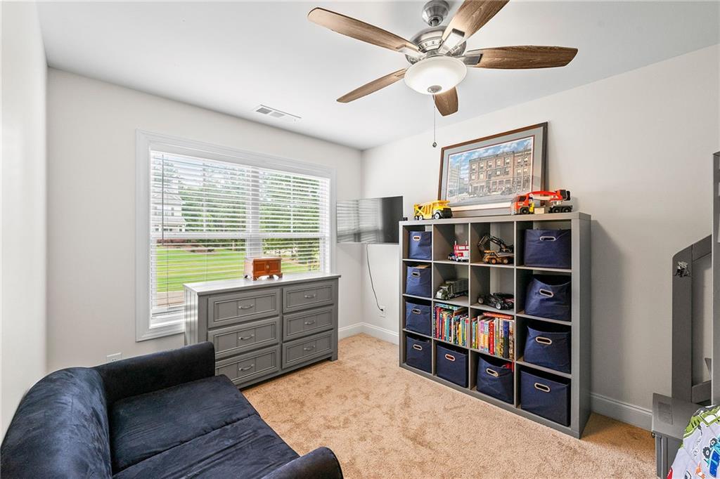 Furnished bonus room with a blue sofa, toy-filled cubbies, and a large window overlooking the lawn.