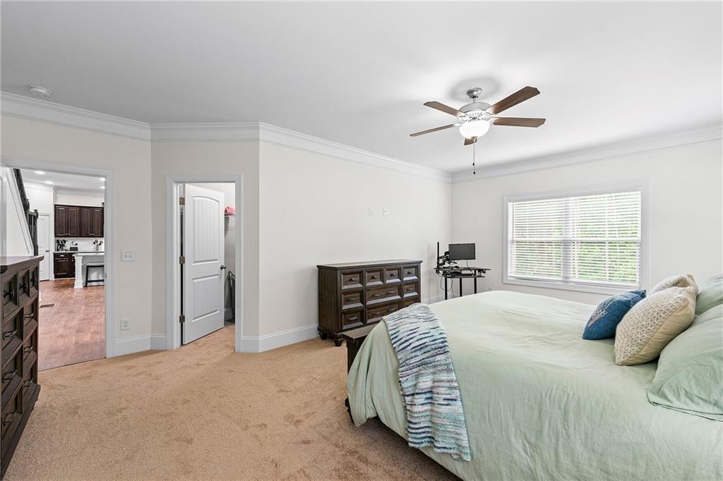 Bedroom with a pale green bedspread, dark wood dresser, and ceiling fan.