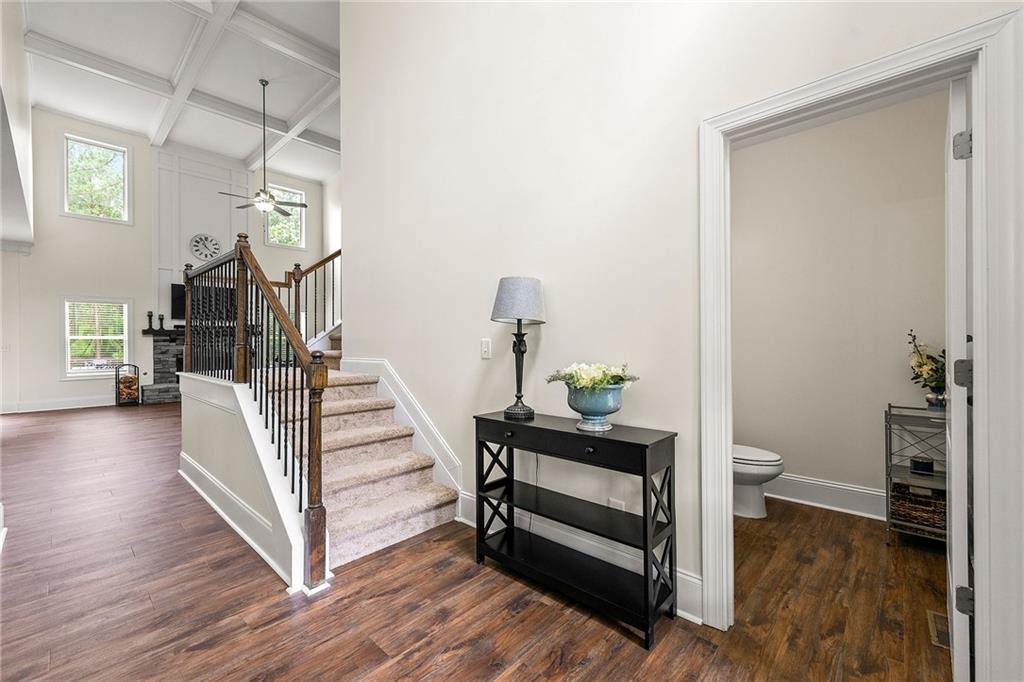 Entryway with a carpeted staircase, dark wood floors, and an open powder room doorway.