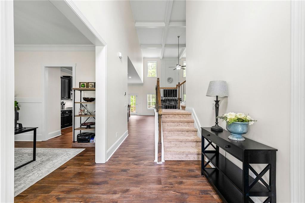 Foyer with hardwood floors, a carpeted staircase, and a console table beside the entry hall.
