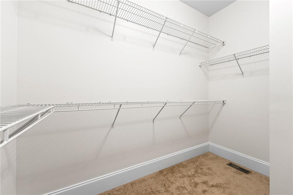 Walk-in closet with wire shelving on three walls and beige carpet.