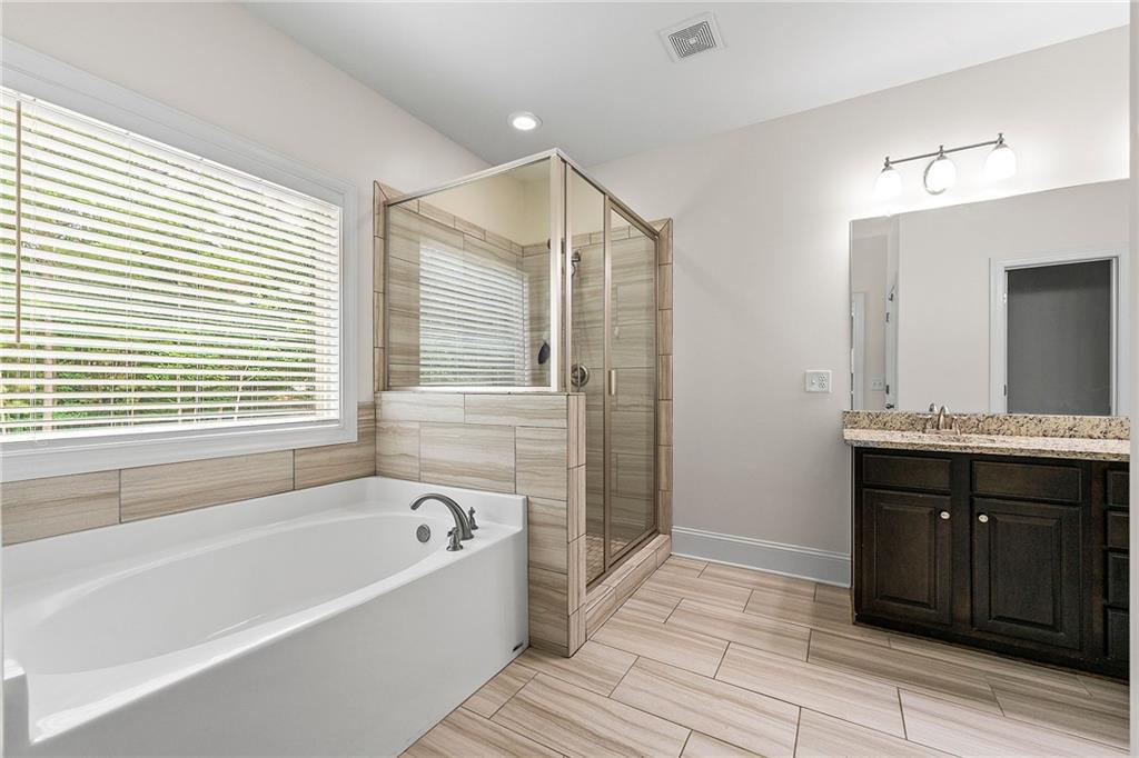 Bathroom with a soaking tub, glass-enclosed tiled shower, and dark wood vanity.