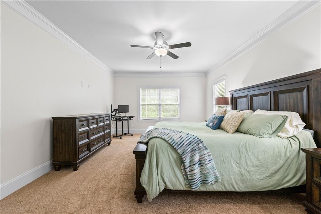Bedroom with a dark wood bed and dresser, green bedding, and a ceiling fan.