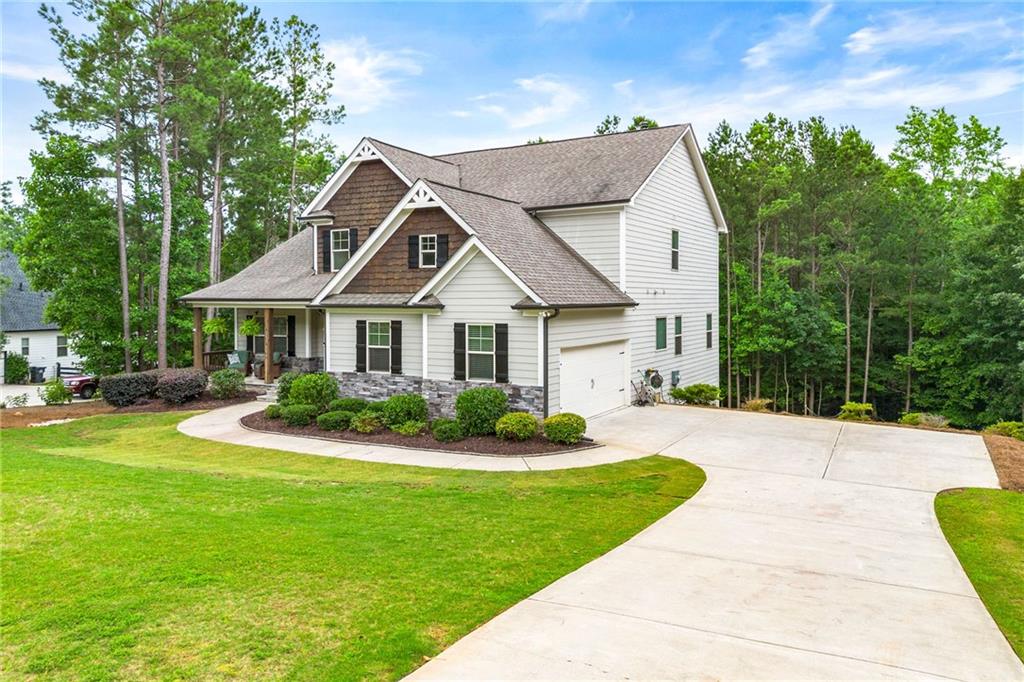 Two-story white house with brown shingle accents, a covered porch, and a curved driveway.