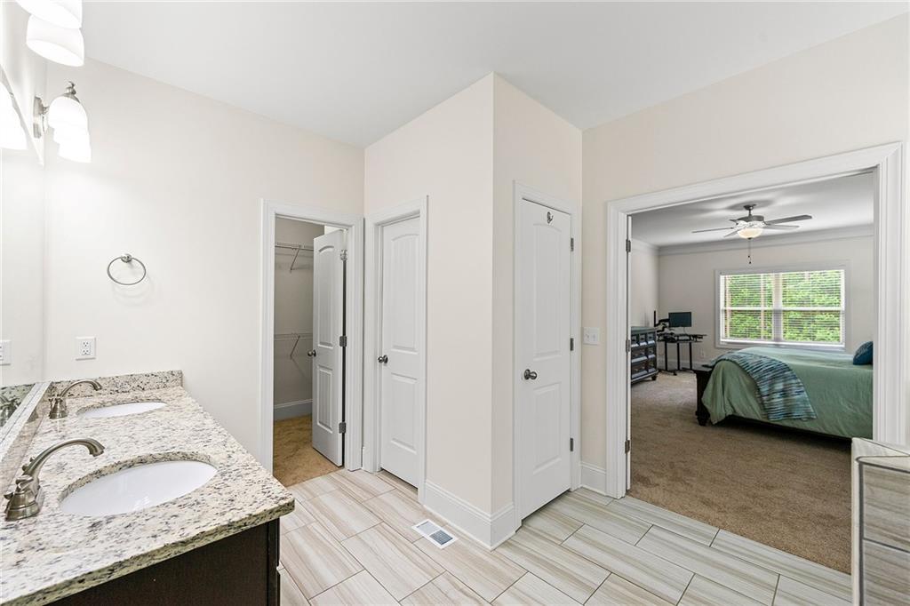 Bathroom with double-sink granite vanity and tiled floor opening onto a bedroom.