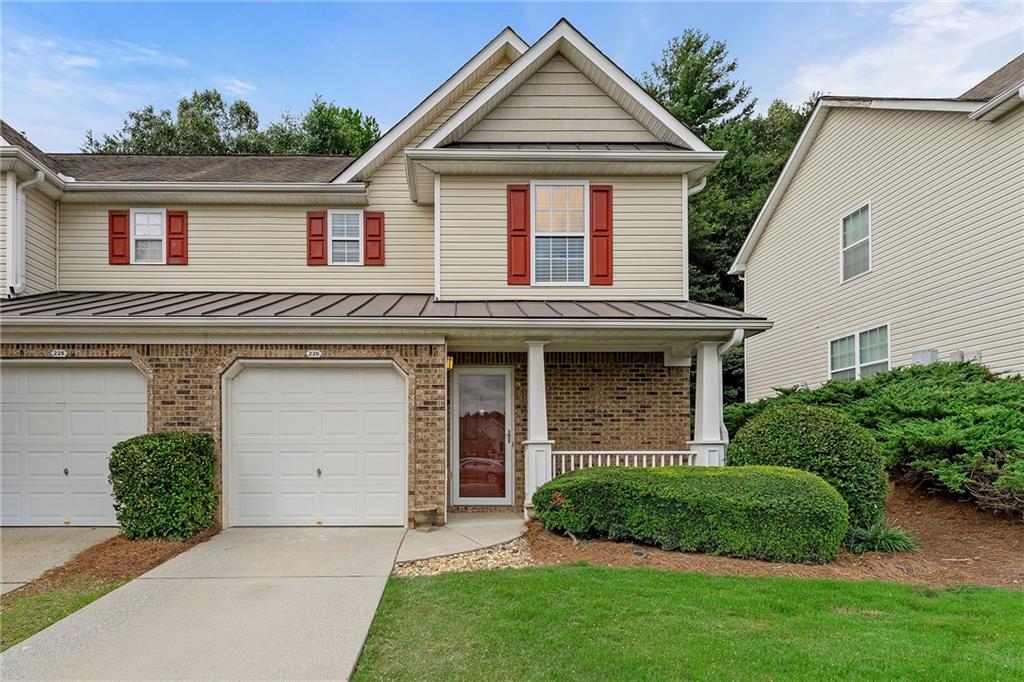 Two-story attached home with brick lower level, red shutters, garage, and covered porch.