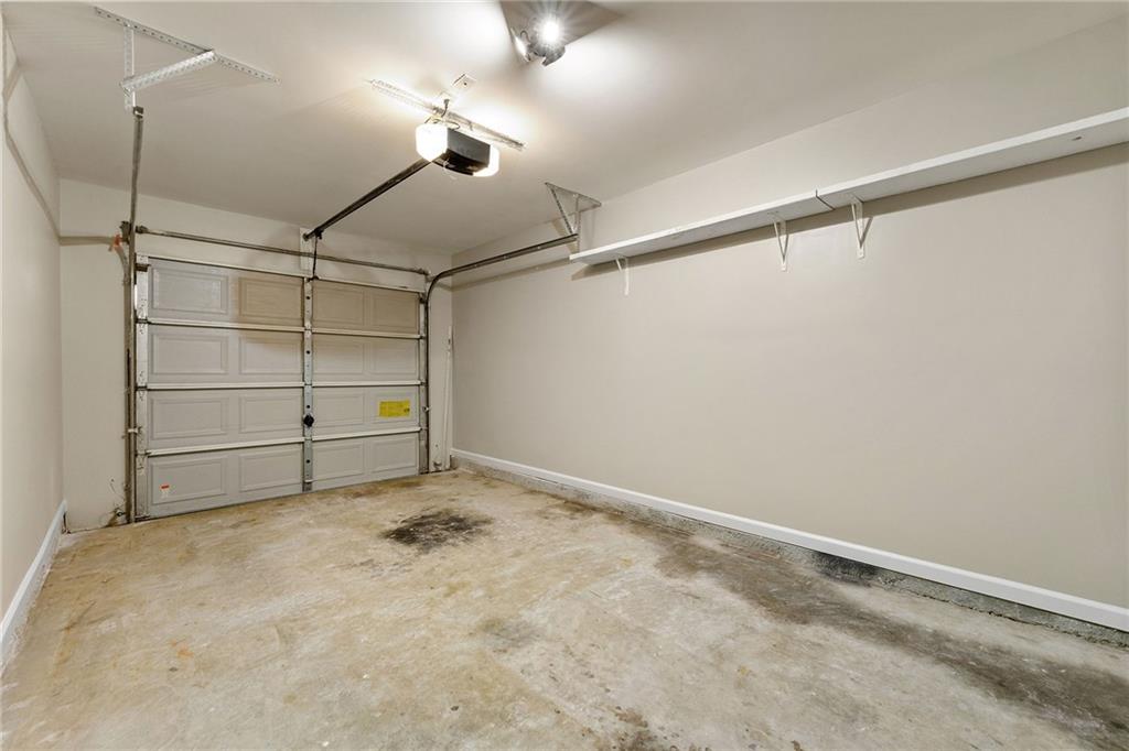 Empty garage with a wall shelf and stained concrete floor.