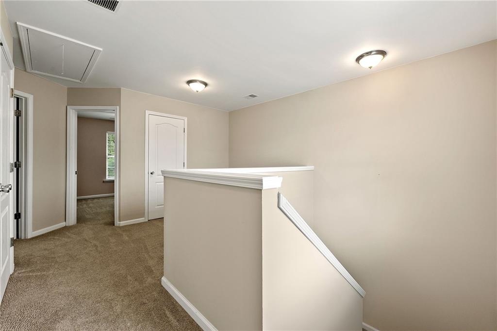 Upstairs hallway with beige carpet, white doors, and a stair railing.
