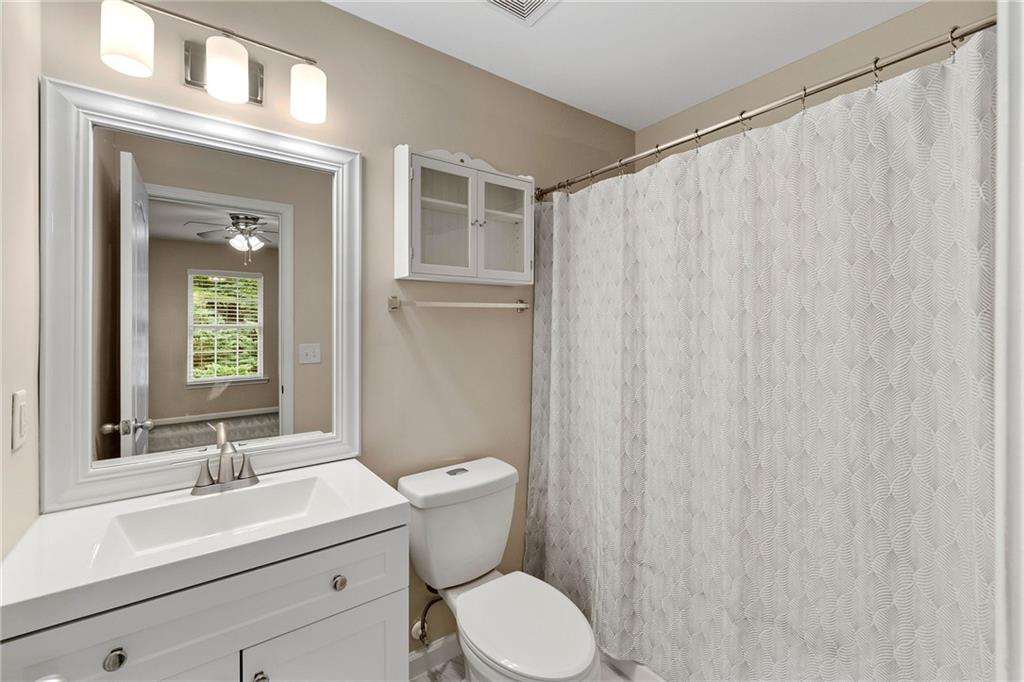 Bathroom with a white vanity, large framed mirror, and patterned shower curtain.