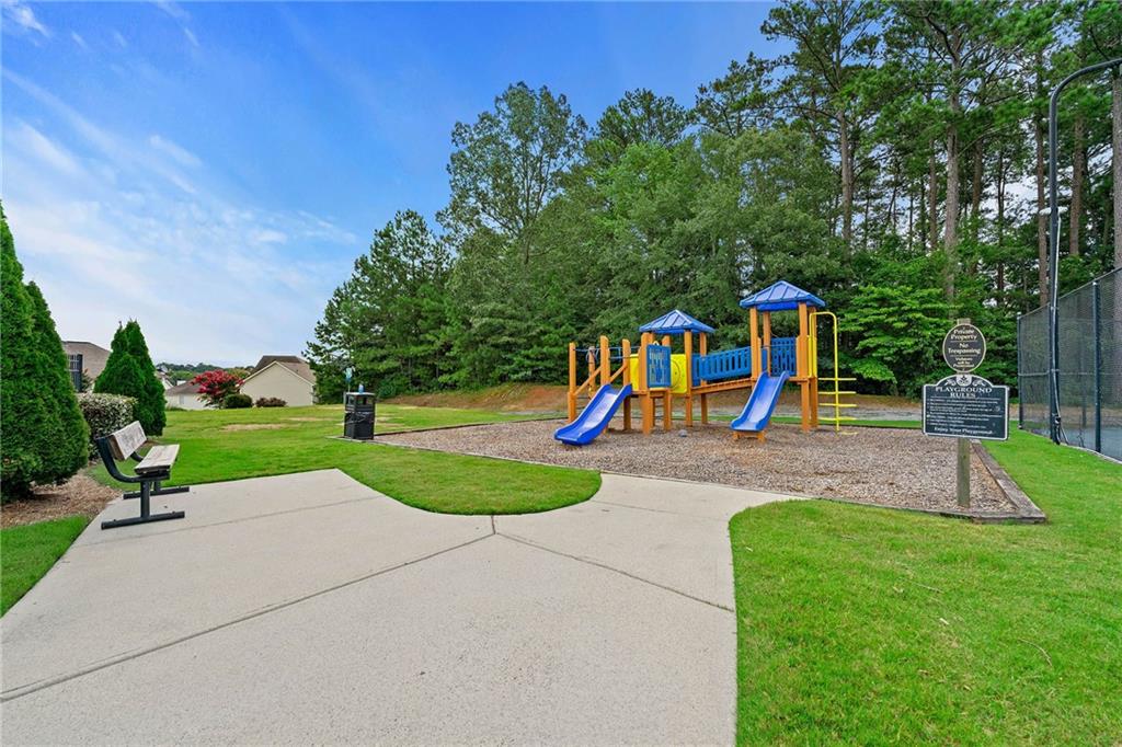 Community playground with blue slides, a colorful climbing structure, and a paved walkway.