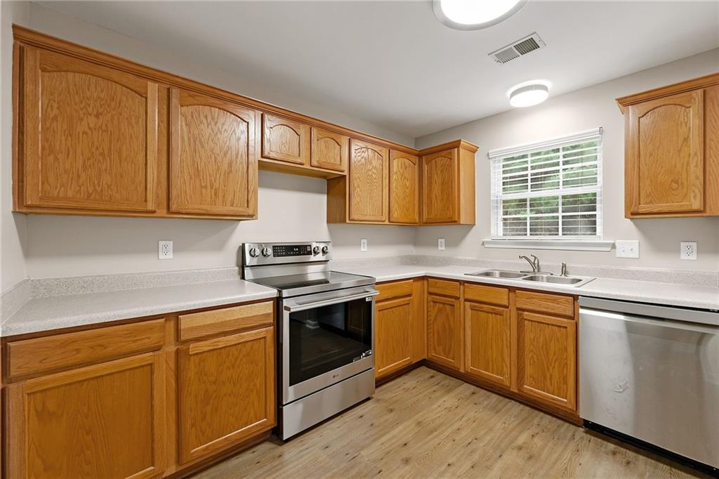 Kitchen with honey-colored cabinets, stainless-steel appliances, and a sink beneath a window.