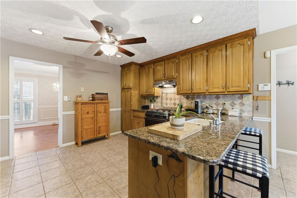 Kitchen with honey-colored cabinets, a granite island, and checkered bar stools.