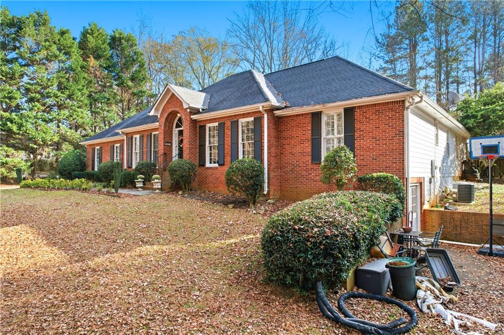 Red brick home with an arched entry, black shutters, and a leaf-covered yard.