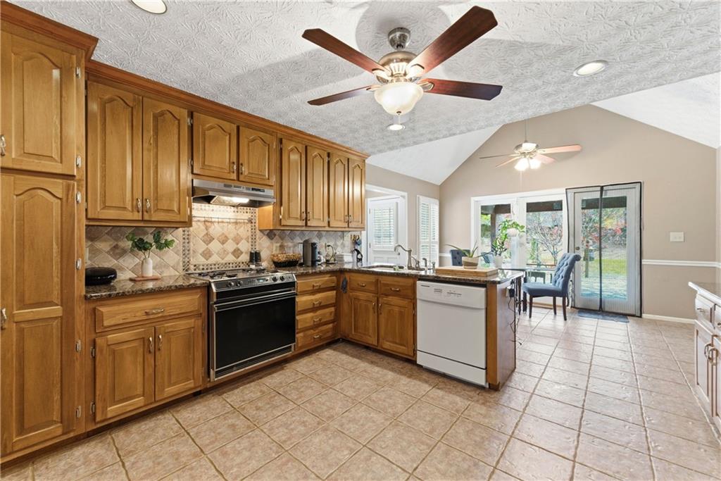 Kitchen with honey-toned wood cabinets, tiled floors, and sliding glass doors to the backyard.