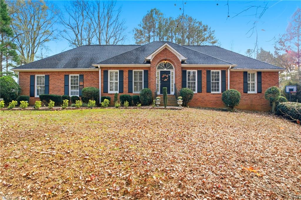 Red brick home with an arched front entrance and leaf-covered lawn.