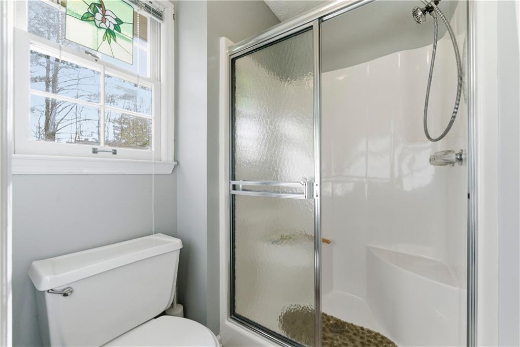 Bathroom with a glass-enclosed shower, pebble floor, and stained-glass window panel.