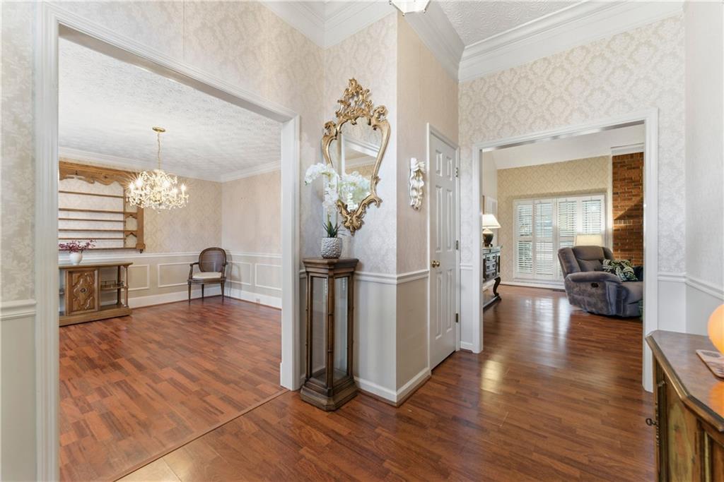 Wood-floored foyer opening to a dining room and living room, with patterned walls and an ornate mirror.