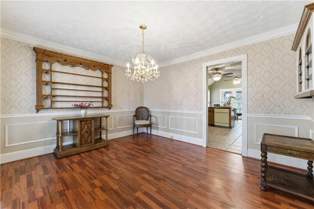 Dining room with hardwood floors, a crystal chandelier, and built-in display shelves beside the kitchen.