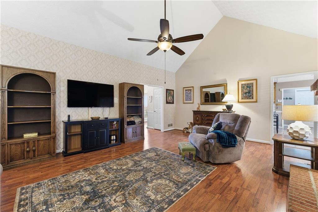 Living room with vaulted ceiling, built-in shelves, hardwood floors, and a patterned area rug.