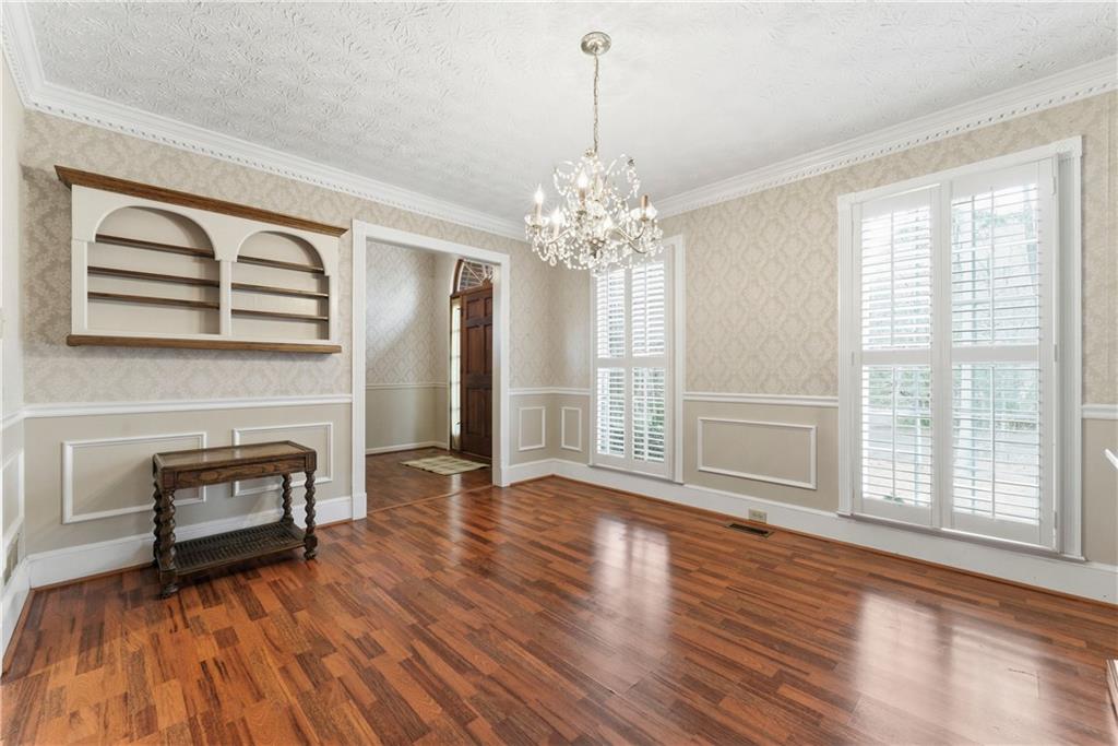 Formal dining room with parquet floors, crystal chandelier, built-in shelves, and plantation-shuttered windows.