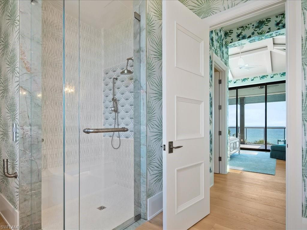 Walk-in shower with patterned tile and an ocean view through the adjoining bedroom.