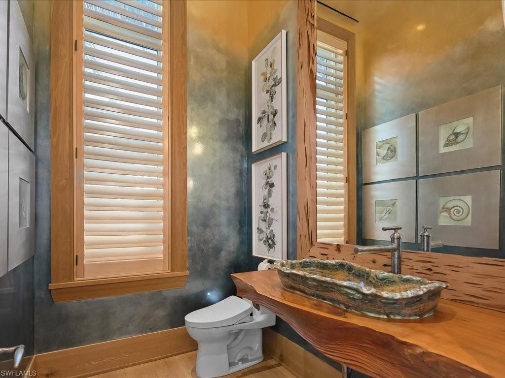 Bathroom with a sculptural wood vanity, stone vessel sink, and plantation shutters.